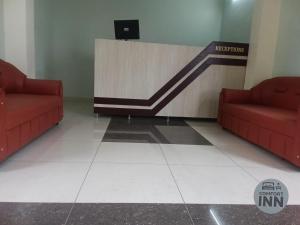 a waiting room with two red couches and a reception counter at Comfort inn Lodge Tirunelveli in Tirunelveli