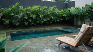 a swimming pool with a bench and a chair and some trees at FLAT NOVO e ACONCHEGANTE in Ribeirão Preto