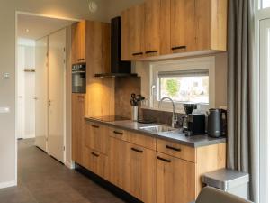 a kitchen with wooden cabinets and a sink at Luxury holiday home surrounded by water and forest in Sint Nicolaasga