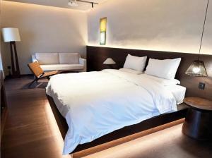 Un dormitorio con una gran cama blanca y una silla. en Chaozhou Meisu Ancient City Store, en Chaozhou