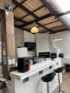 a kitchen with white counter tops and bar stools at Canto das Toninhas Guest House in Ubatuba