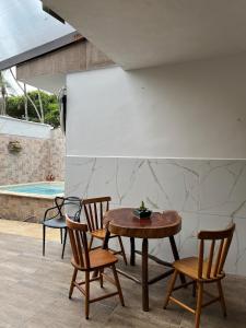 una mesa y sillas junto a una piscina en Canto das Toninhas Guest House, en Ubatuba