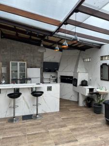 una gran cocina con encimeras blancas y taburetes de bar en Canto das Toninhas Guest House, en Ubatuba