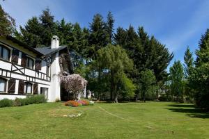 a white house with a yard with grass and trees at Del Prado in San Carlos de Bariloche