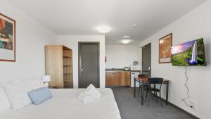 a bedroom with a white bed and a kitchen at Alpine Heights 18 in Mount Hotham