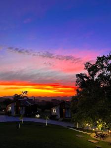 a sunset over a house with the sun setting at Le Mont Chalés in Bento Gonçalves