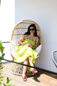 a woman in a yellow dress sitting in a rattan chair at Luna Mare Boutique Seaside in Borsh