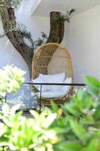 a rattan chair and a glass table in front of a tree at Luna Mare Boutique Seaside in Borsh