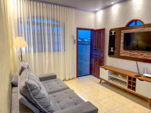 ein Wohnzimmer mit Couch und Flachbildfernseher in der Unterkunft Casa na prainha de Mambucaba. Uma quadra do mar. in Paraty