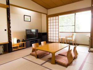 a living room with a table and chairs and a tv at LiVEMAX RESORT izukogen in Ito