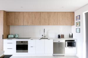 Una cocina con gabinetes blancos y electrodomésticos de acero inoxidable. en Family Friendly - Close to new stadium, en Christchurch