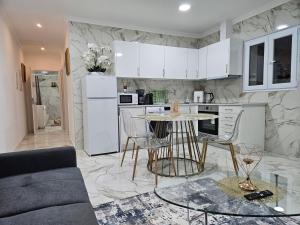 a kitchen with white cabinets and a table and chairs at Casa da Linda in Ponta Delgada