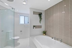 Un baño con bañera, inodoro y ducha. en Skywater Retreat - 3 bedroom, en The Entrance 8 fotos más