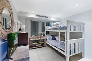1 dormitorio con litera blanca y espejo en Skywater Retreat - 3 bedroom, en The Entrance