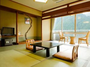 un soggiorno con tavolo, sedie e TV di Hinotani Onsen Misugi Resort a Tsu