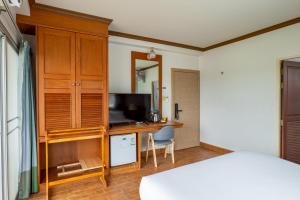 a bedroom with a bed and a desk with a television at Krabi River Hotel in Krabi