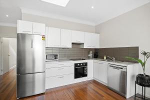 a kitchen with white cabinets and a stainless steel refrigerator at Port Melbourne Victorian Cottage in Melbourne