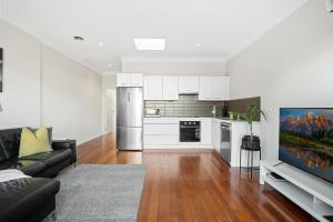 a living room with a black couch and a kitchen at Port Melbourne Victorian Cottage in Melbourne +8 photos