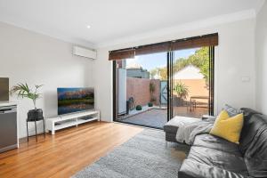 a living room with a couch and a tv at Port Melbourne Victorian Cottage in Melbourne