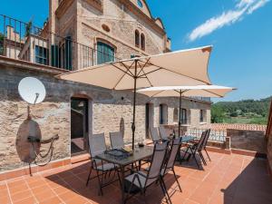 a patio with a table and chairs and an umbrella at Mansion in Castellnou near Pedraforca Mountains in Castellnou de Bages