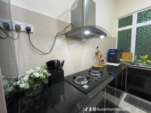 a kitchen with a black counter top with a stove at BULAN Homestay Melaka in Malacca