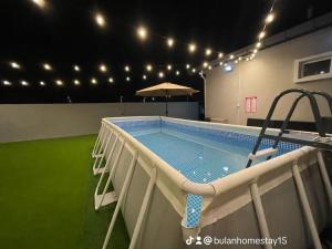 a swimming pool with an umbrella in a building at BULAN Homestay Melaka in Malacca