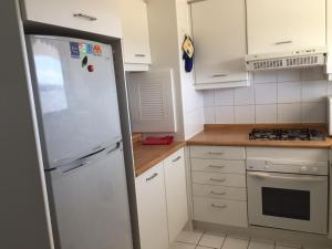 cocina con armarios blancos y nevera blanca en Condominio San Alfonso del Mar, en Algarrobo