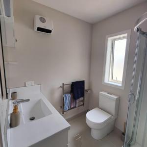 a white bathroom with a toilet and a sink at Fairburn Hideaway in Cambridge +6 photos