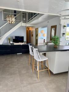 a kitchen and living room with a counter and chairs at Villa Téloam- Charmante villa avec piscine et vue mer in Schœlcher