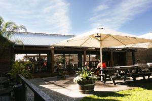 a picnic table with an umbrella in front of a building at Avon Valley Inn Hotel in Gloucester