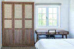 a bedroom with a desk and a bed and a window at Perolas Villas Resort - Ke Ga Bay in Phan Thiet