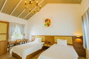 a bedroom with two beds and a chandelier at Perolas Villas Resort - Ke Ga Bay in Phan Thiet