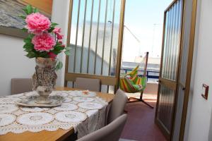 a table with a vase with pink flowers on it at Palazzo Primavera in Porto Cesareo