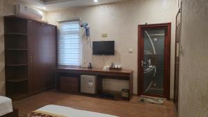 Un dormitorio con un escritorio con televisión y una ventana. en Ha Long Lotus Hotel, en Ha Long