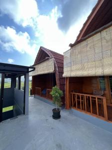 a large wooden building with a potted tree on a patio at Lumbung Kembar Guest House, Nyanyi in Munggu