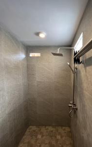 a bathroom with a shower with a tiled wall at Lumbung Kembar Guest House, Nyanyi in Munggu
