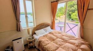 a bedroom with a bed and a large window at Petit Hotel Kashikojima Harbor in Shima