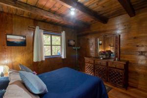a bedroom with a blue bed and a window at Cabaña Vista al Cielo - Cabañas Terrazul in Pinal de Amoles