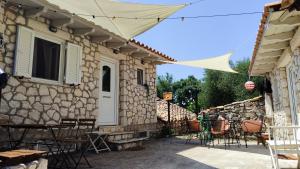 a patio with tables and chairs in a stone house at Το Λαϊνάκι by Fox Tale Guest House in Fternón