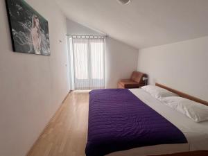 a bedroom with a bed with a purple blanket at Apartment Danijela in Vodice