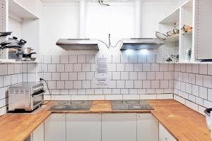 a kitchen with white tiled walls and white cabinets at Pint On Punt Backpackers in Melbourne