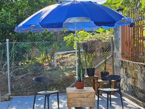 a blue umbrella with three chairs and a table with plants at Two Bedroom Holiday Home- Olosara Sigatoka Guest House in Singatoka