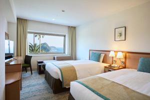 Una habitación de hotel con dos camas y una ventana. en Shimoda Tokyu Hotel, en Shimoda 33 fotos más