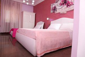 ein Schlafzimmer mit einem großen Bett mit einer rosa Wand in der Unterkunft Palazzo Primavera in Porto Cesareo