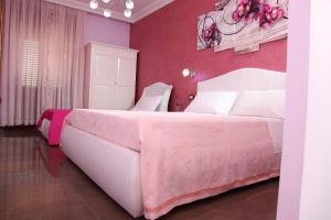 a bedroom with a large bed with a pink wall at Palazzo Primavera in Porto Cesareo