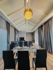 een eetkamer met een tafel, stoelen en een kroonluchter bij V2 Poolvilla Cha-am Huahin in Ban Hup Kaphong