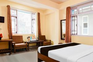 a hotel room with a bed and a desk and window at Hotel O De Sikkim Regency in Gangtok