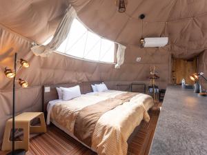 ein Schlafzimmer mit einem Bett in einem Zelt in der Unterkunft LiVEMAX RESORT Sakurajima Sea Front in Tarumizu
