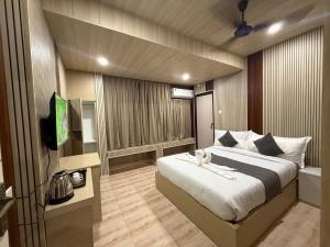 a bedroom with a large bed and a television at Hotel Alohi Grand in Guwahati