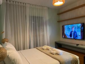 a bedroom with a tv and a bed with towels at Casa Mar III in João Pessoa